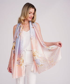 Blush pink oblong scarf featuring a vibrant abstract print for a soft, seasonal statement look. Crafted from lightweight chiffon with a silk-feel finish and delicate hemline edging for a polished drape. Suitable for versatile styling as a neck scarf, shawl, or wrap.